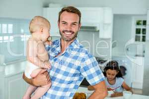 Portrait of happy father carrying son in kitchen