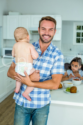 Happy father carrying son with daughter having breakfast