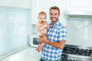 Happy father carrying standing by kitchen counter