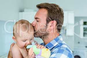 Father kissing playful son in kitchen at home