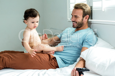 Father sitting with baby boy on bed