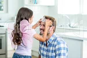 Daughter in angel costume putting crown on father head