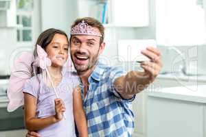 Father taking selfie with daughter in angel costume