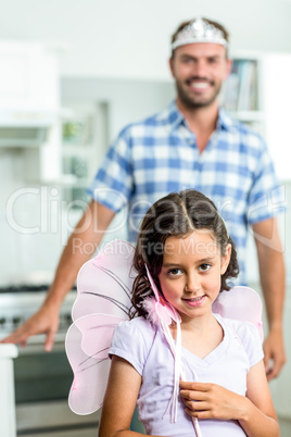 Portrait of girl in angel costume while father in background