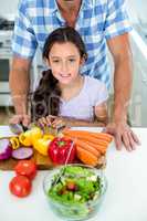 Daughter with father by vegetables at kitchen table