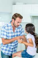 Father pointing while talking with daughter in kitchen