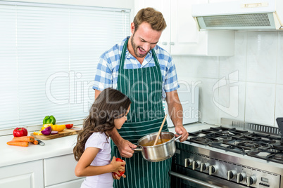 Father and daughter preparing food in kitchen