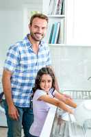 Daughter washing utensils while father standing beside her