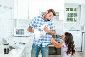 Father wiping container while daughter pulling him