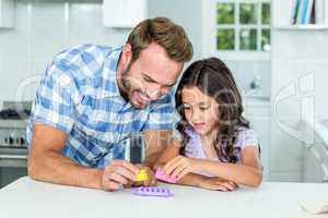 Father and daughter playing with toy block at table