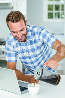 Man pouring coffee in cup at table in kitchen