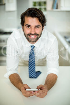 Businessman using cellphone while leaning at table