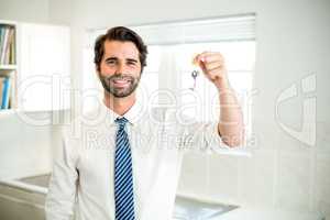Confident businessman holding house key at home