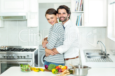 Couple embracing while preparing food in kitchen