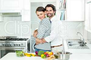 Couple embracing while preparing food in kitchen