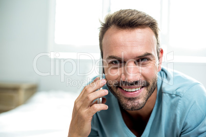 Portrait of happy man using cellphone on bed