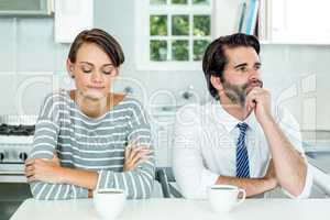 Unhappy couple sitting at table in kitchen