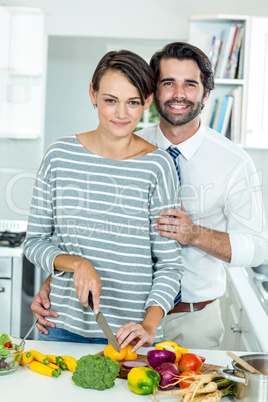 Happy couple cutting vegetables at table in kitchen