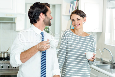 Businessman interacting with happy woman while drinking coffee