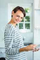 Beautiful woman smiling while reading book in kitchen