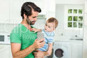 Father showing mobile phone to cute baby boy