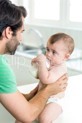 Baby boy drinking milk while father holding him