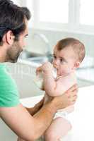 Baby boy drinking milk while father holding him