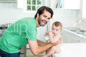 Happy father with son drinking milk at kitchen table
