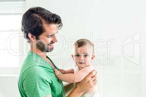 Father smiling while carrying son at home