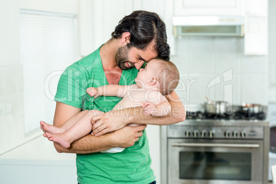 Father carrying baby boy in kitchen at home Father carrying baby boy in kitchen at home