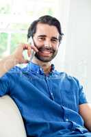 Handsome man talking on mobile phone while resting at home