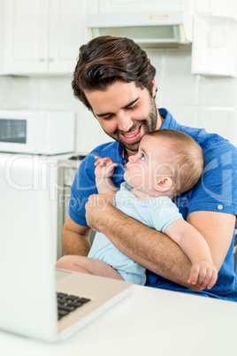 Man sitting with son by laptop at table