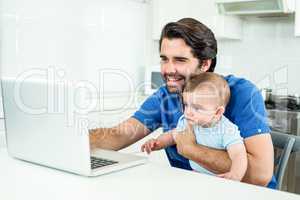 Man using laptop while sitting with son at table