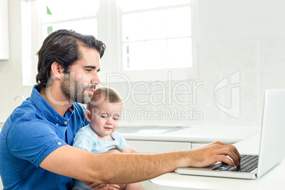 Man using laptop while sitting with son at home