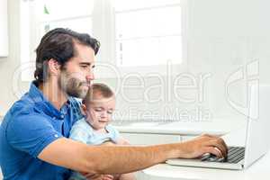 Man using laptop while sitting with son at home