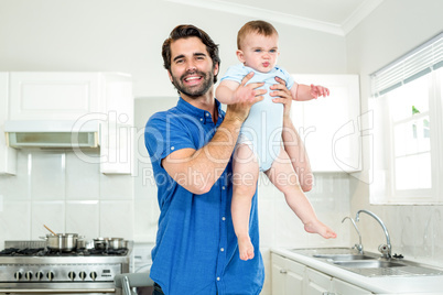 Father playing with son by kitchen counter at home