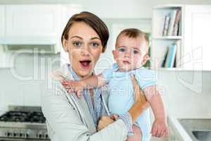 Surprised mother carrying son in kitchen at home