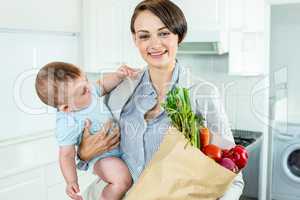 Businesswoman carrying son while holding vegetables
