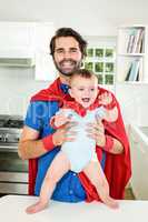 Happy father and son in superhero costume at home