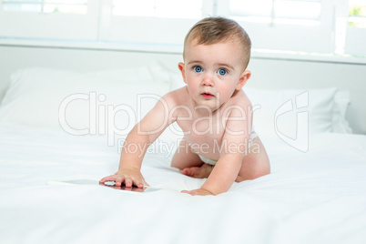 Cute baby boy playing with digital tablet on bed