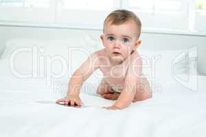 Cute baby boy playing with digital tablet on bed