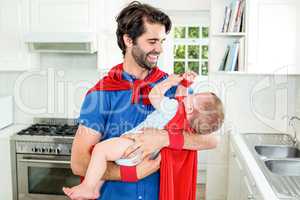 Father and son in superhero costume playing in kitchen