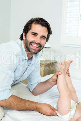 Father changing diaper of son on bed at home