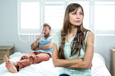 Upset woman sitting while man in background