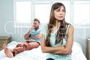 Upset woman sitting while man in background