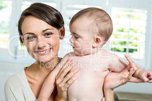 Mother smiling while carrying son at home