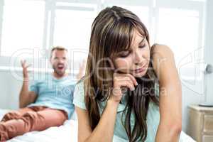 Upset woman sitting while man shouting in background