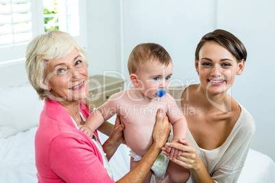 Grandmother and mother with baby boy on bed