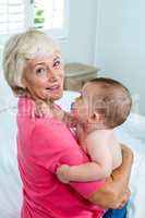 Grandmother carrying baby boy on bed