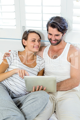 Smiling couple using digital tablet on bed Smiling couple using digital tablet on bed